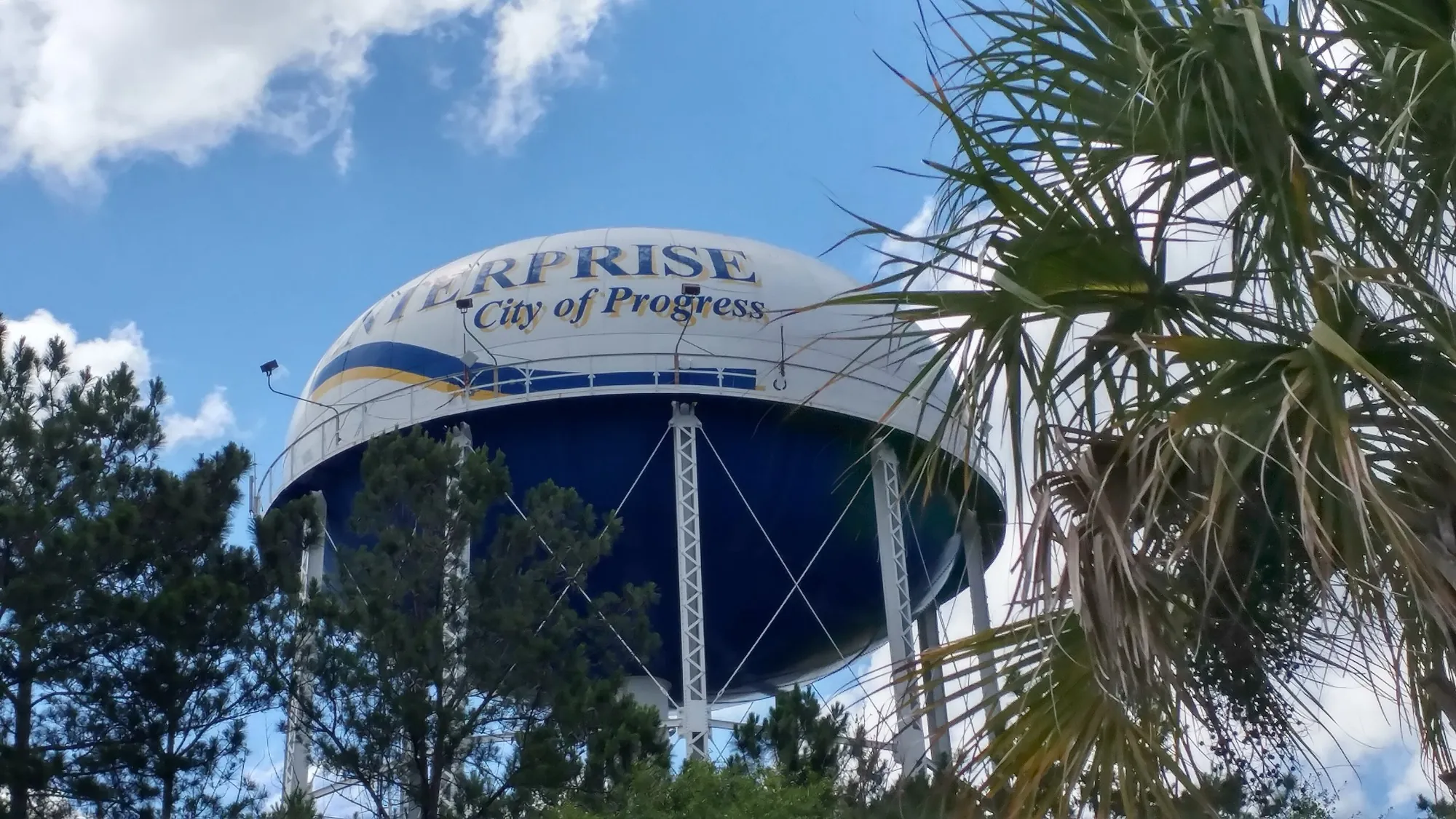 The Enterprise water tower, painted with the words City of Progress, rising behind palm fronds