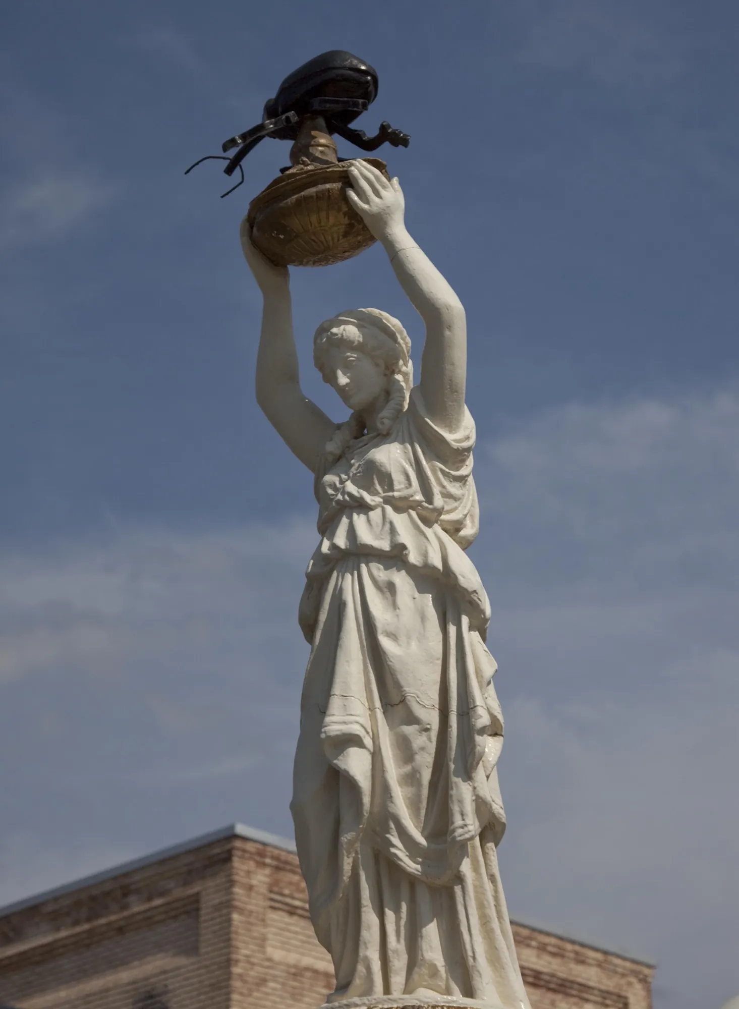 The Boll Weevil Monument in downtown Enterprise: a classical figure holding a boll weevil aloft against a blue sky